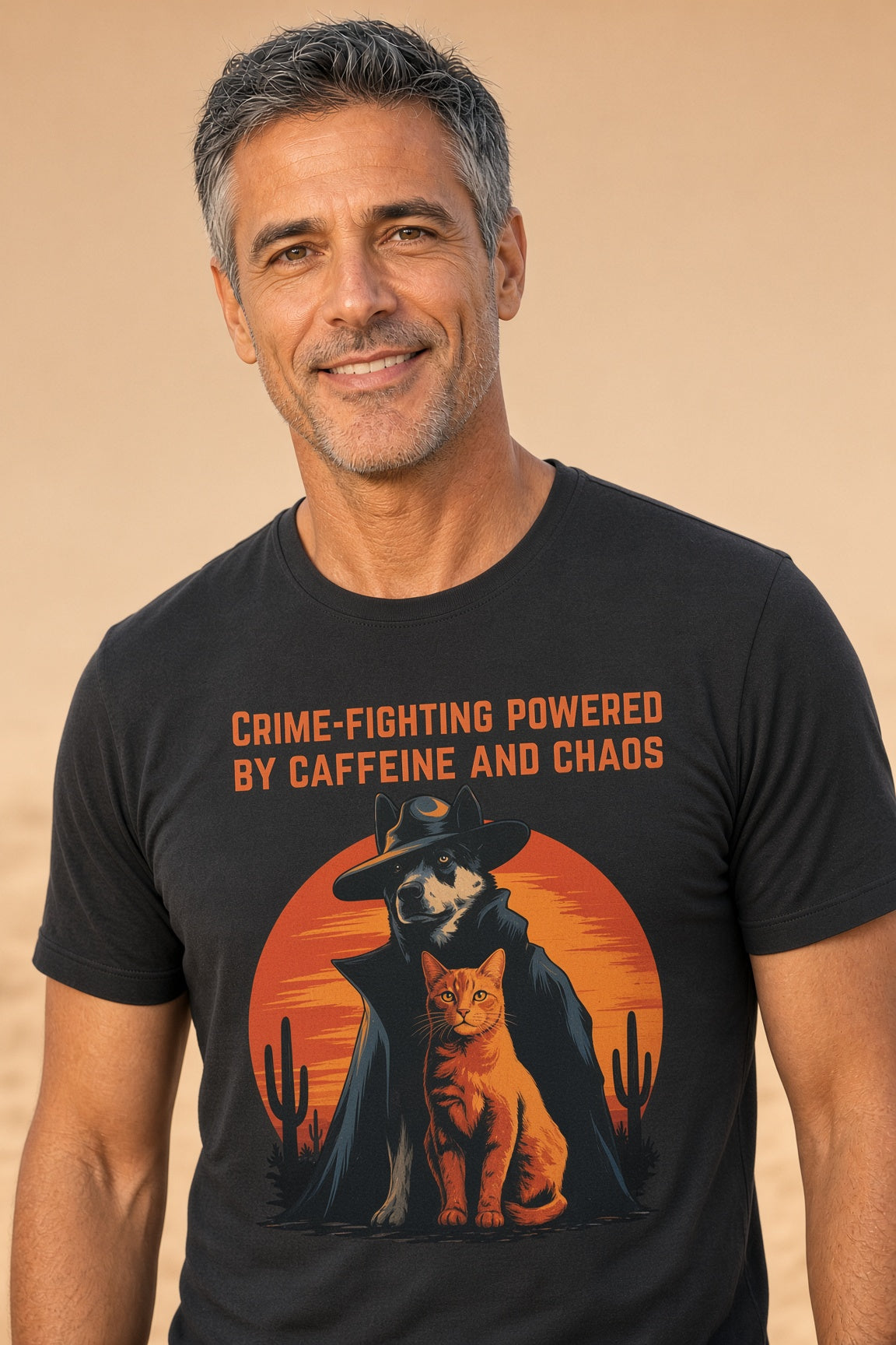 Man smiling while wearing a black t-shirt with a detective dog and orange cat graphic with the text 'Crime-Fighting Powered by Caffeine and Chaos.'