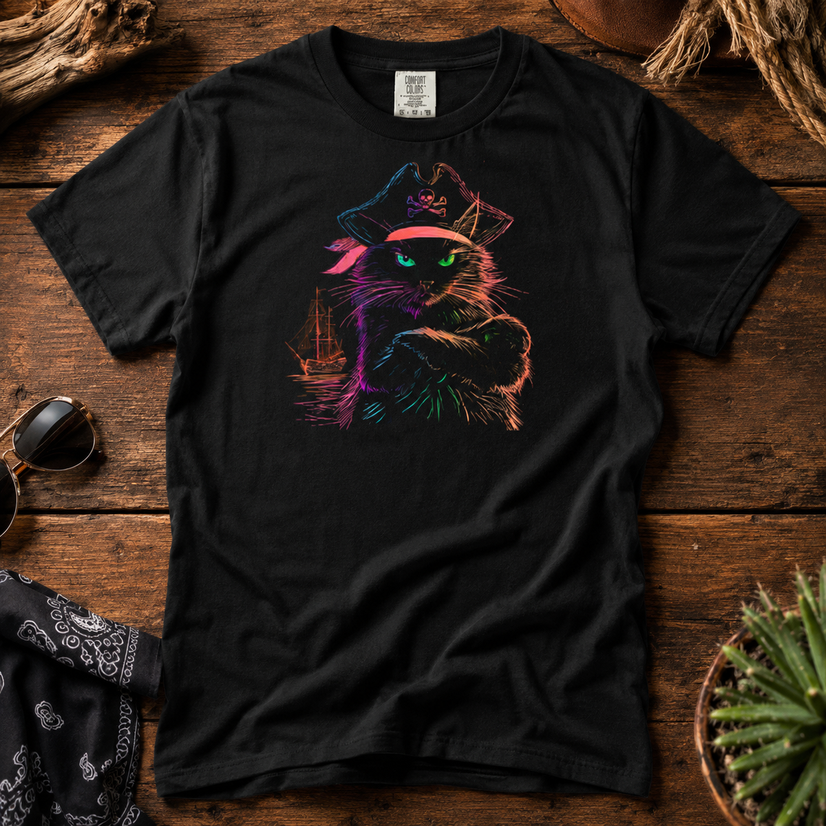 Close-up of a black t-shirt with a colorful pirate cat design on a wooden surface.