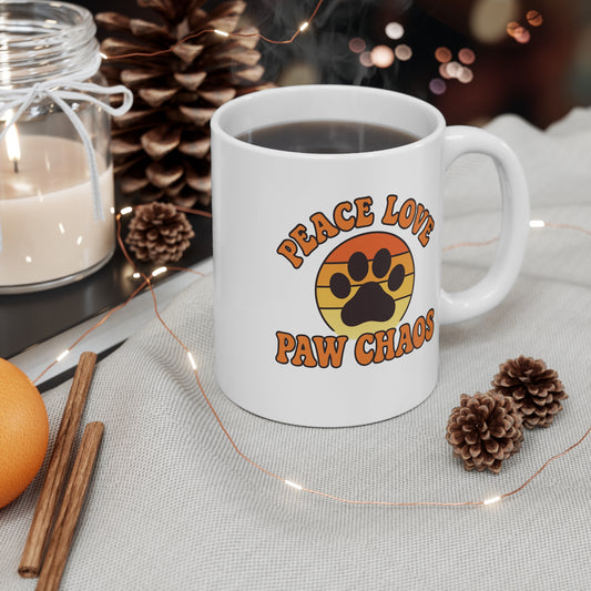 White mug with 'Peace Love Paw Chaos' design on a table with decorative items