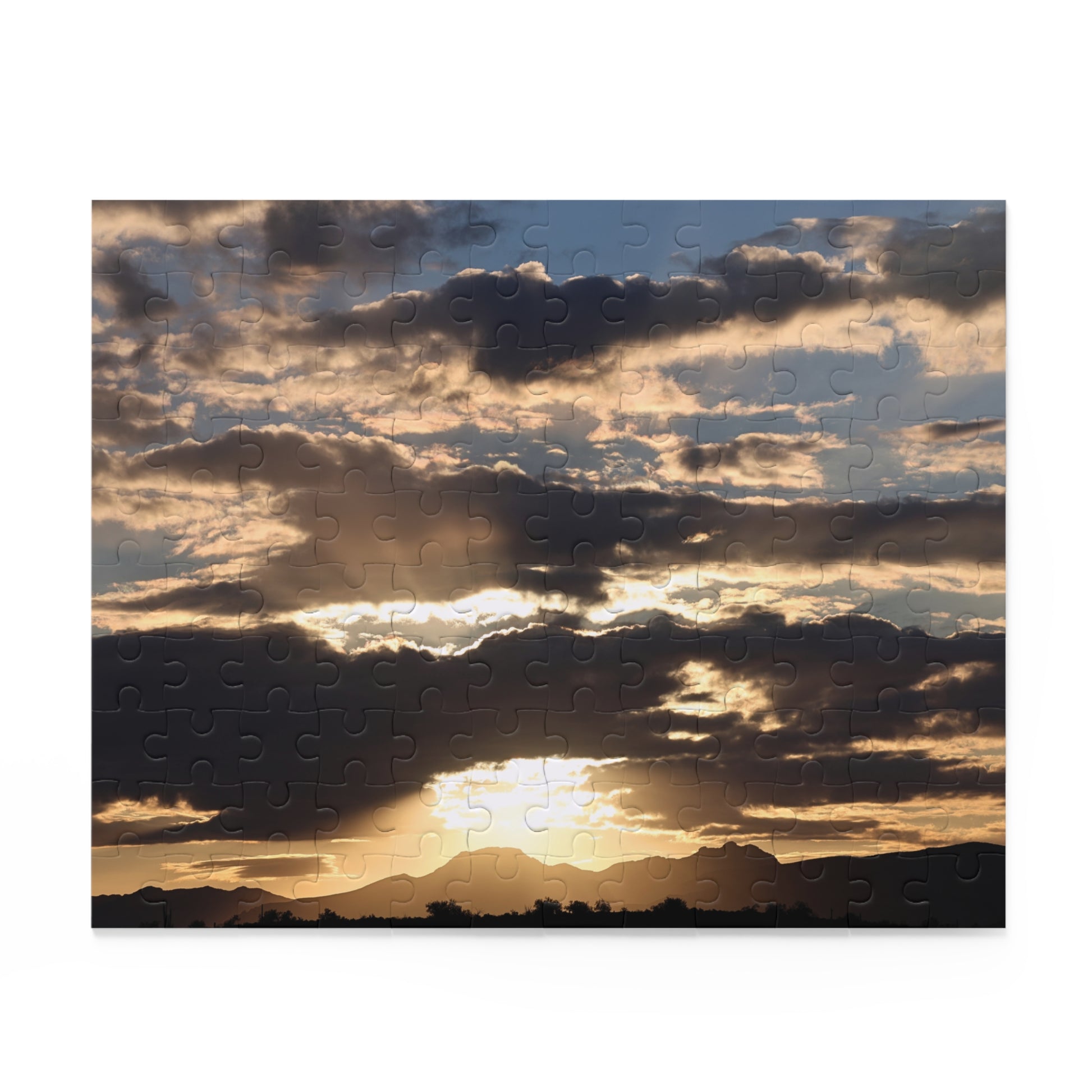 Jigsaw puzzle with a completed image of a sunset over mountains and clouds.
