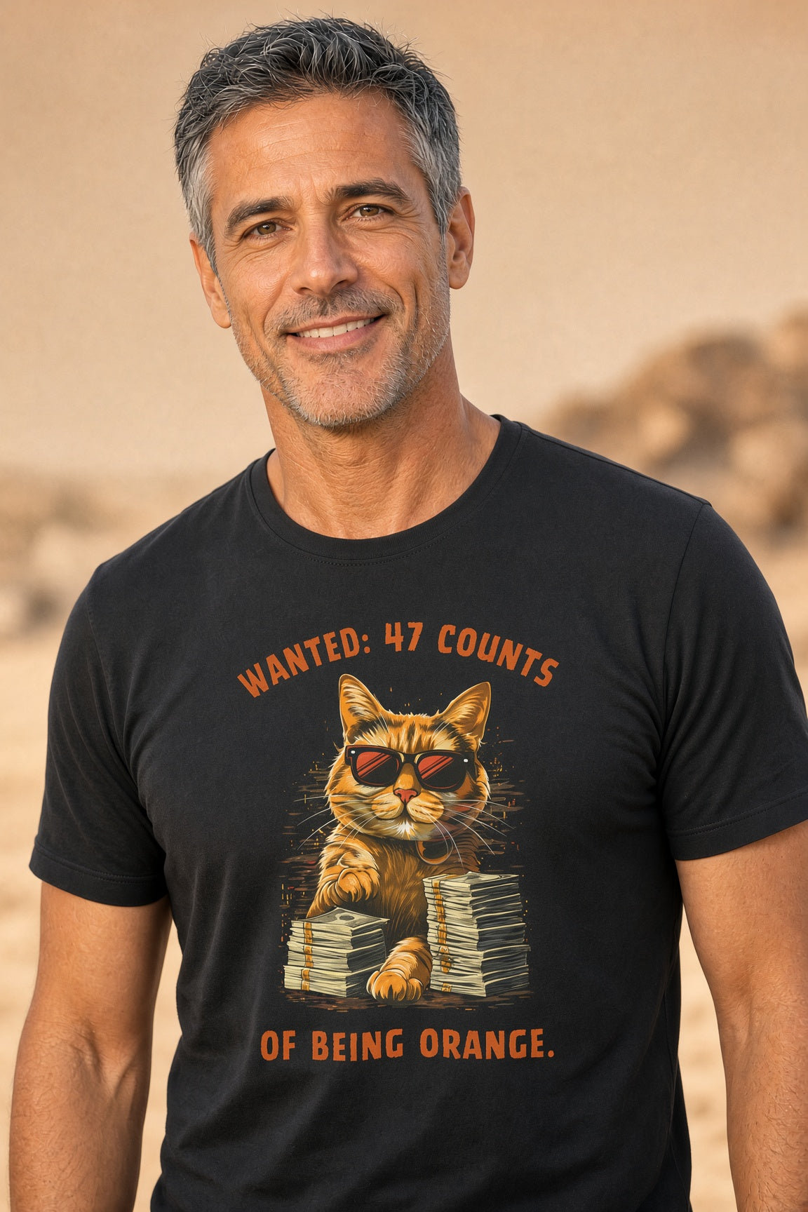 Close-up of a man smiling while wearing a black t-shirt with a cat graphic and the text 'Wanted: 47 Counts of Being Orange.'