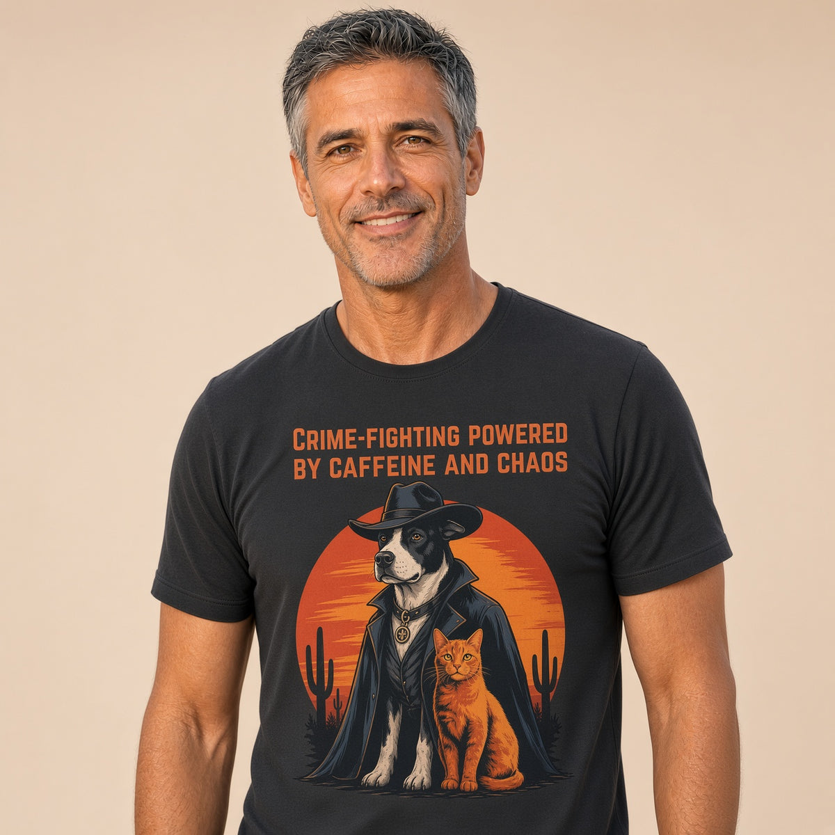 Man wearing a black shirt with a dog and cat graphic design with the text 'Crime-Fighting Powered by Caffeine and Chaos.'
