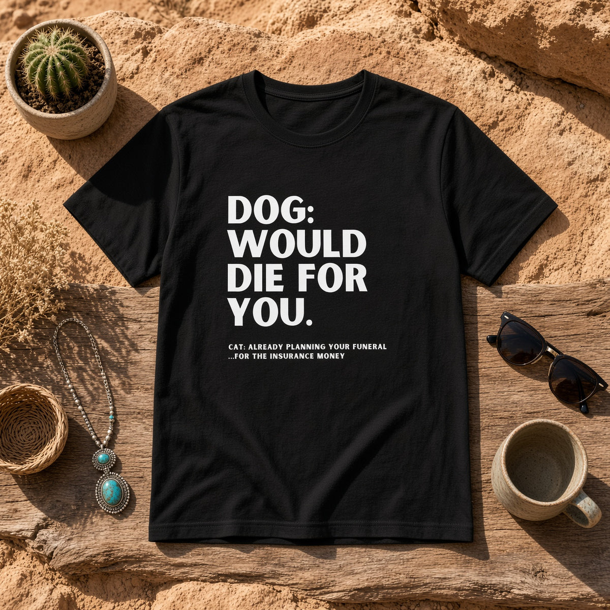 Black t-shirt laid flat on a rustic surface with funny dog and cat text.
