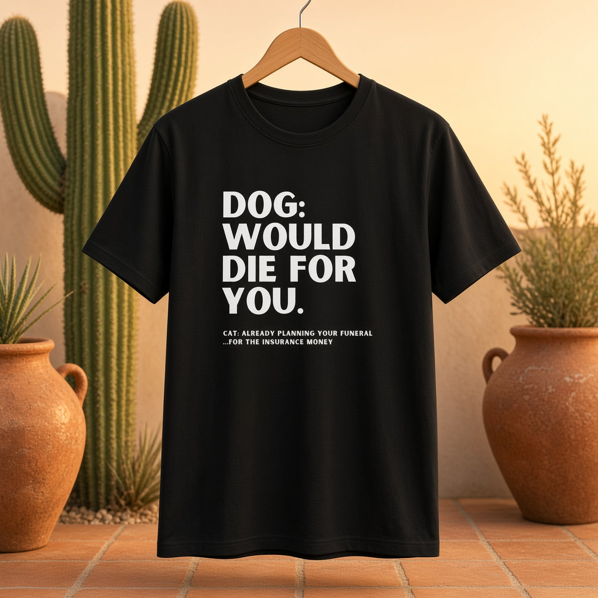 Black t-shirt hanging with humorous dog and cat text in a desert setting.