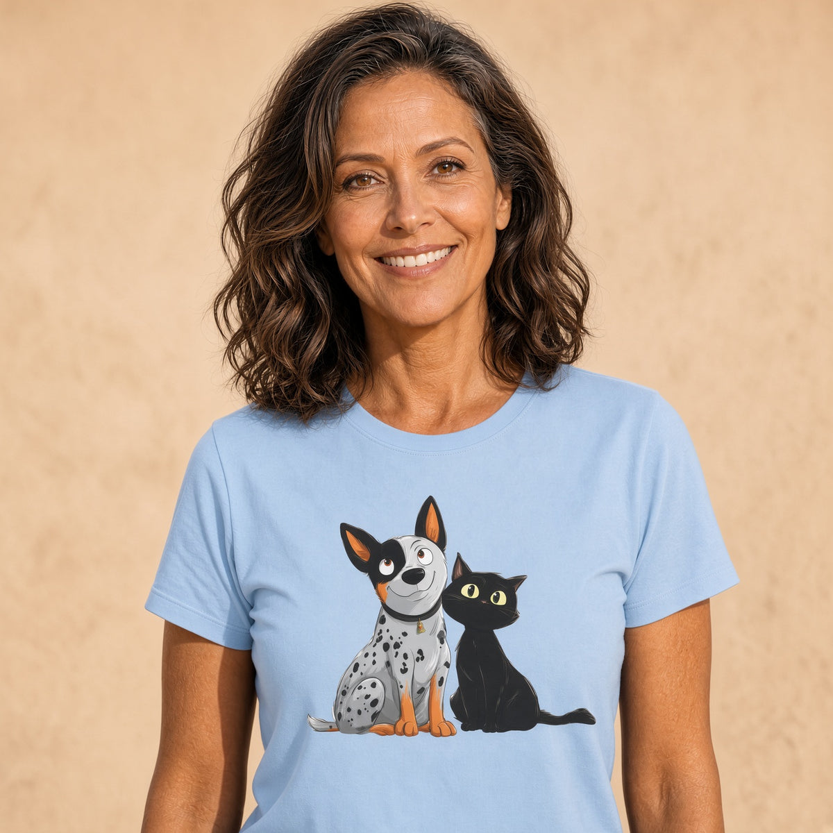 Woman smiling in a light blue tee featuring a playful dog and cat illustration.