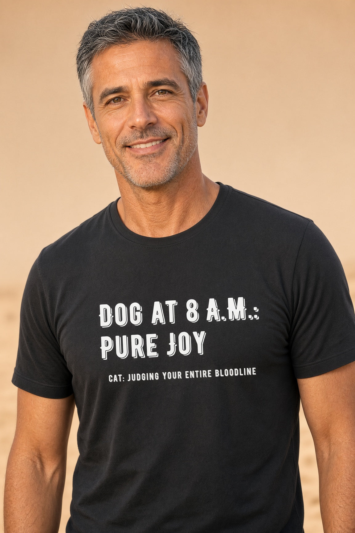 Man smiling while wearing a black t-shirt with the text 'DOG AT 8 A.M.: PURE JOY' and 'CAT: JUDGING YOUR ENTIRE BLOODLINE'