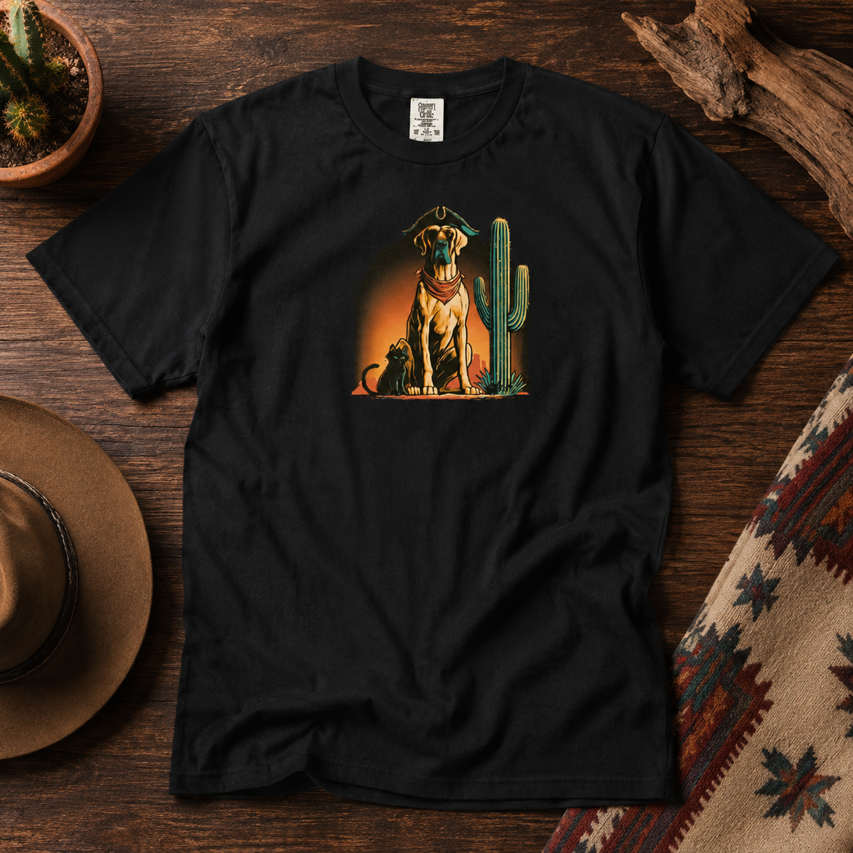 Black t-shirt featuring a dog and cactus design laid flat on a wooden surface.