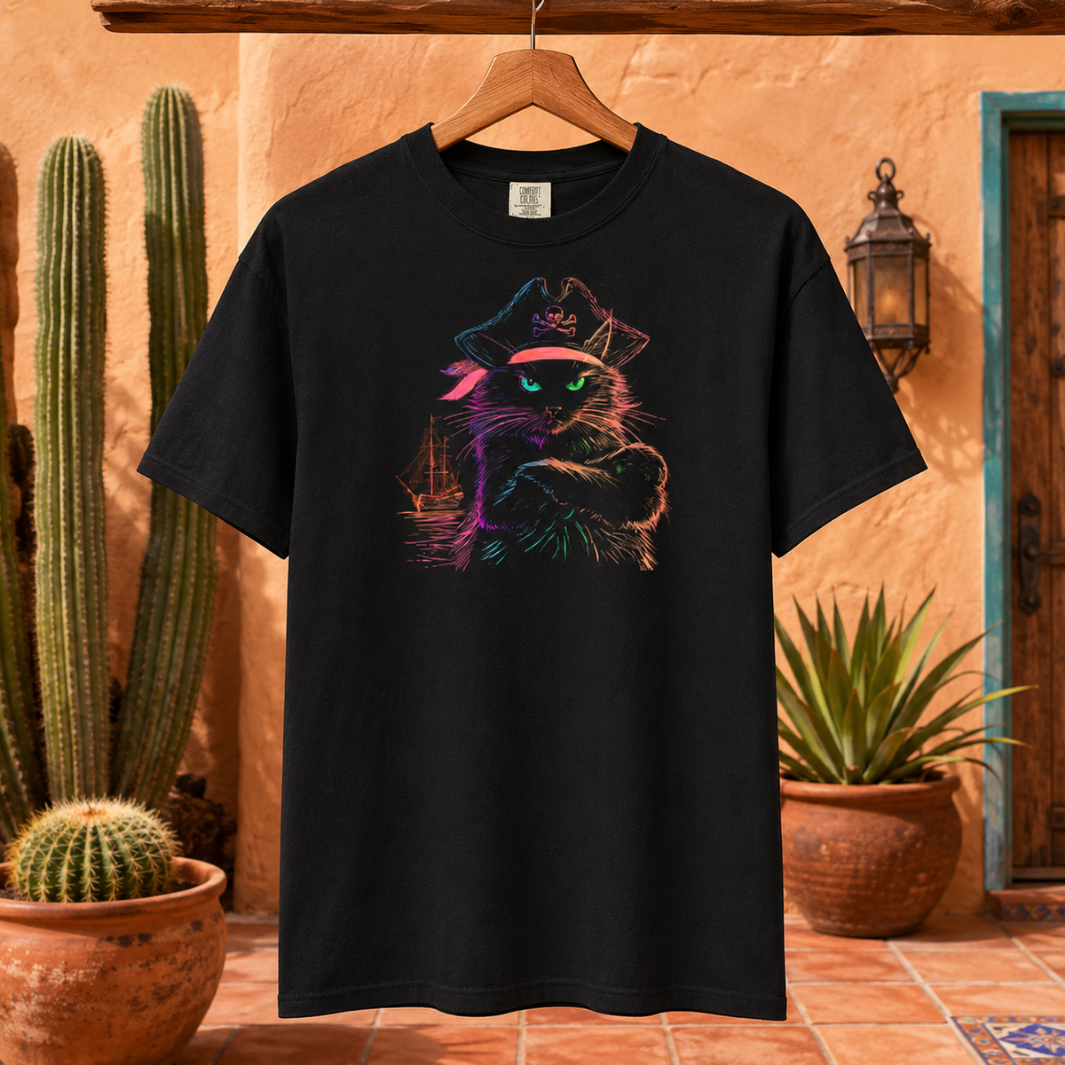 Black t-shirt with a colorful pirate cat design hanging against a desert backdrop.