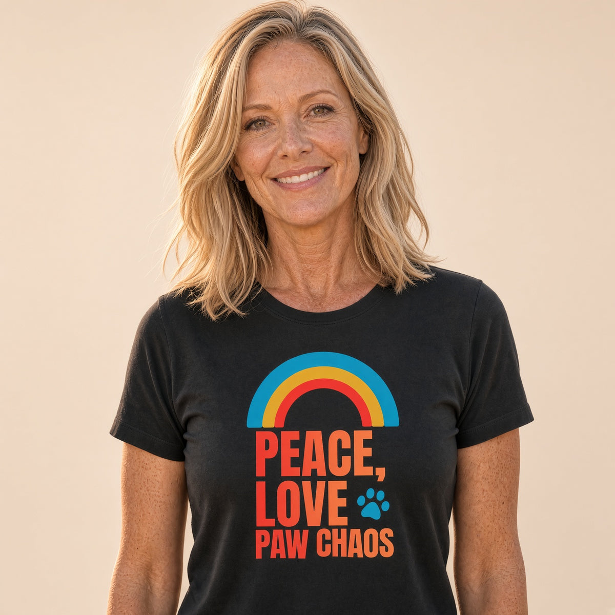 Woman smiling in a black t-shirt with a rainbow and text 'Peace, Love, Paw Chaos'.