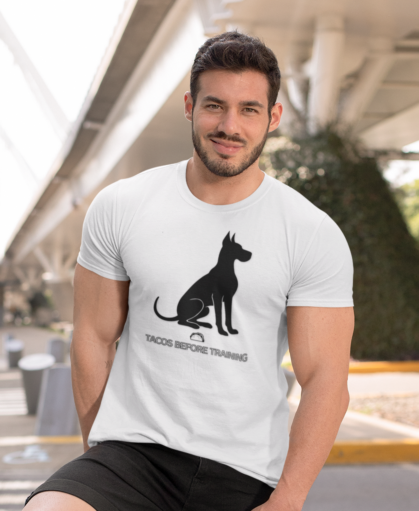 Man wearing a white t-shirt with white Great Dane silhouette and text reading Tacos Before Training