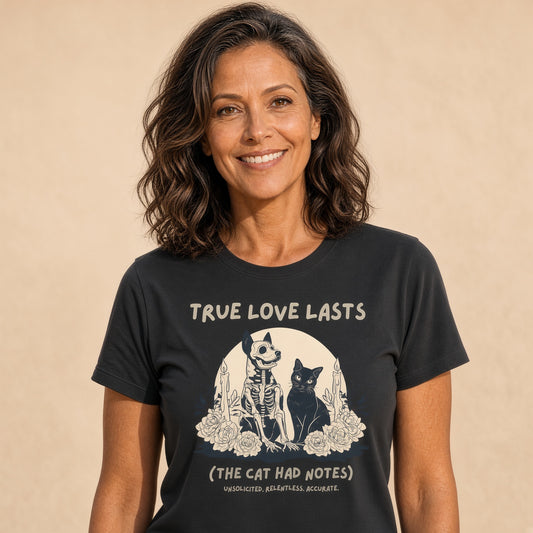 Woman smiling in a black tee featuring a skeleton dog and black cat design with the text 'True Love Lasts (The Cat Had Notes)'.