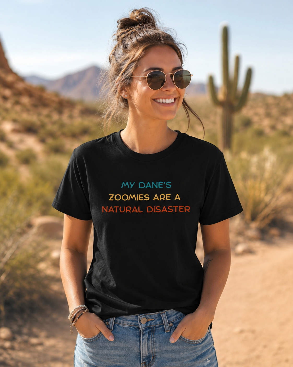 Woman wearing a funny Great Dane zoomies t-shirt outdoors in a sunny Arizona desert setting with cactus and warm Southwest scenery.