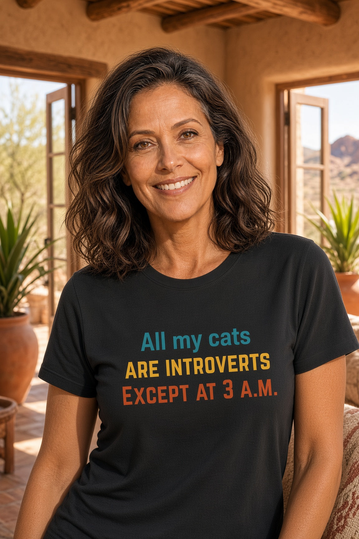 Woman smiling while wearing a black shirt with colorful text about introverted cats.