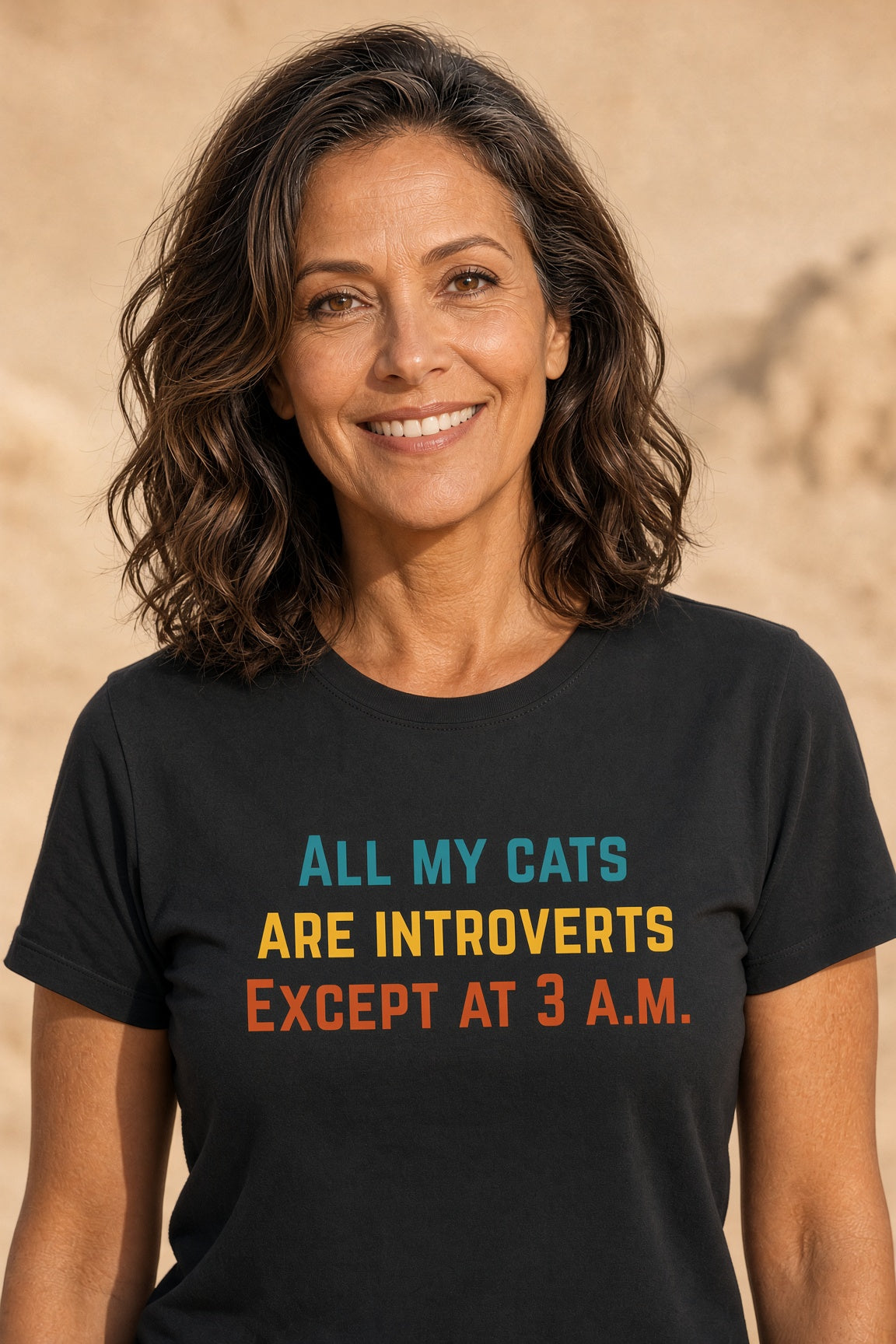 Woman wearing a black t-shirt with colorful text reading 'All My Cats Are Introverts Except at 3 A.M.'