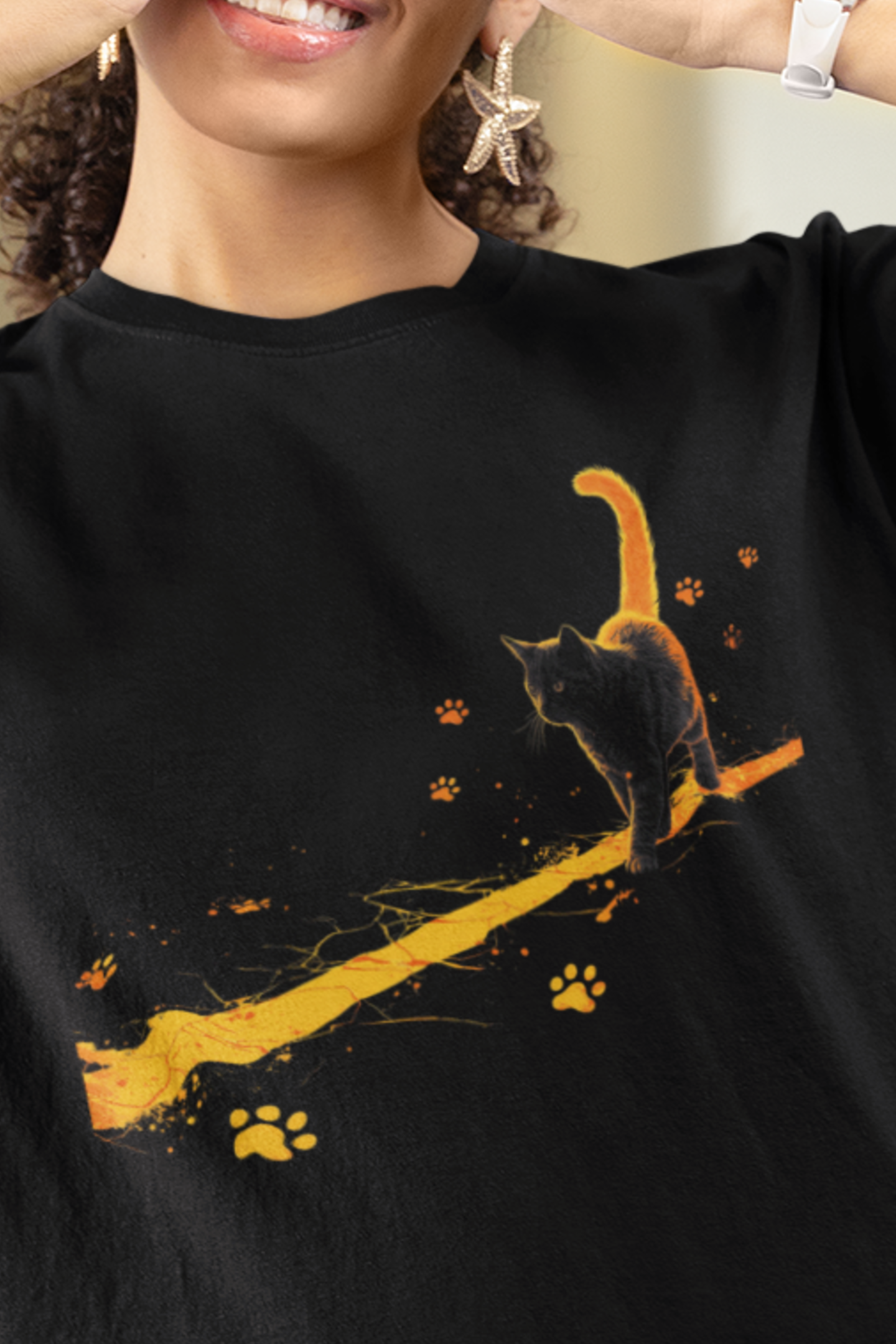 Chaos on a Hot Streak Stray Tee black cat graphic shirt with glowing orange trail and paw prints, worn by a person.