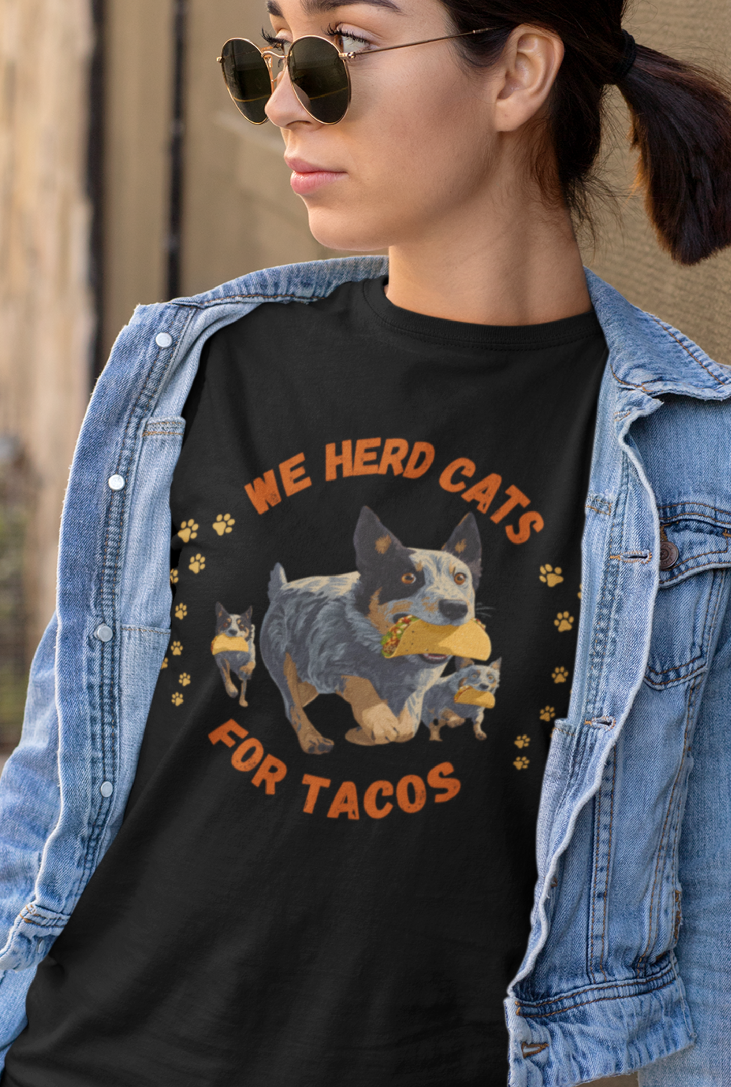 Person wearing a black t-shirt with Blue Heeler dog herding cats with tacos and text reading We Herd Cats for Tacos