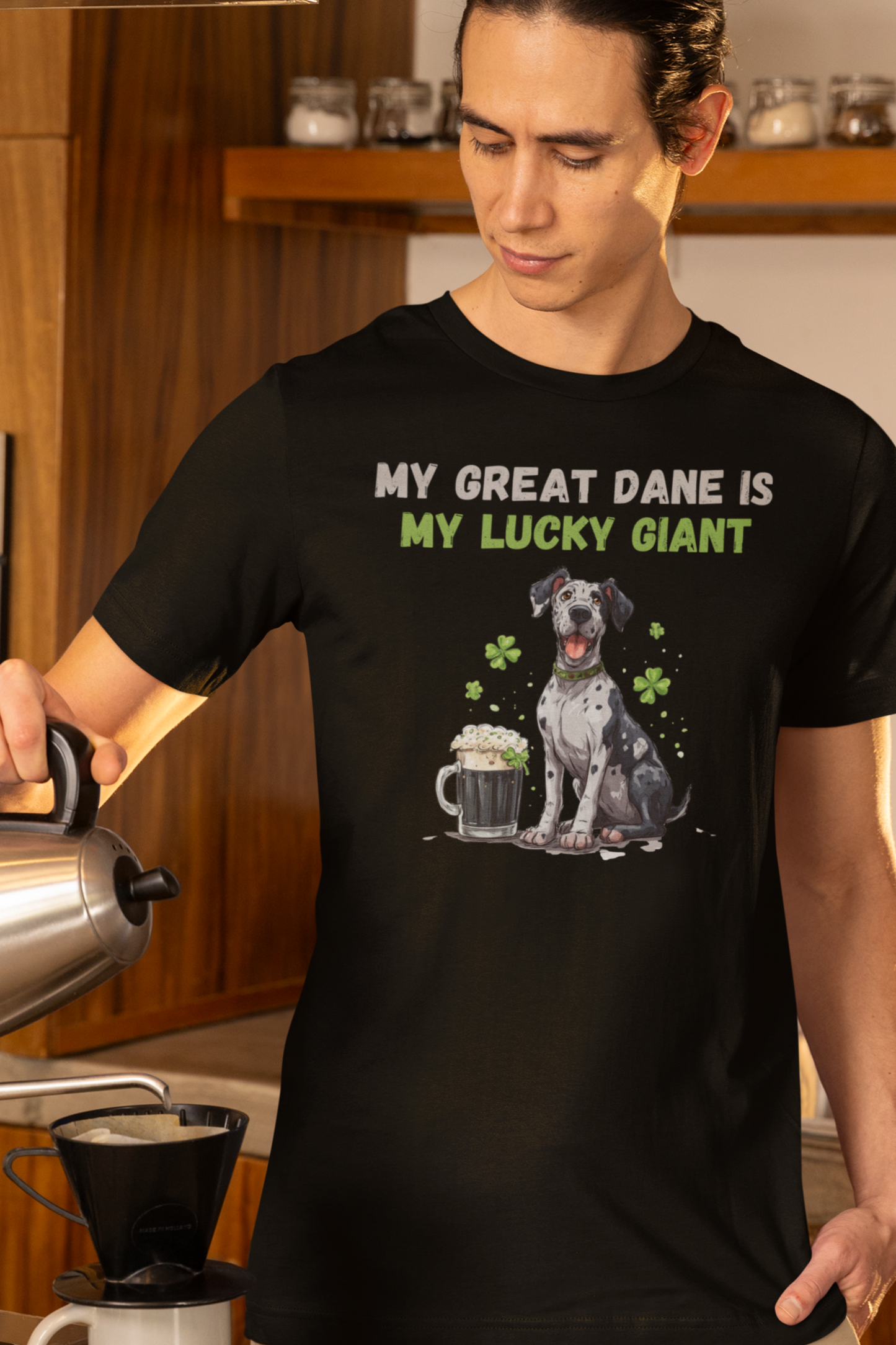 Person wearing a black Great Dane St Patrick’s Day t-shirt with beer and shamrocks, unisex tee front view in a kitchen. 
