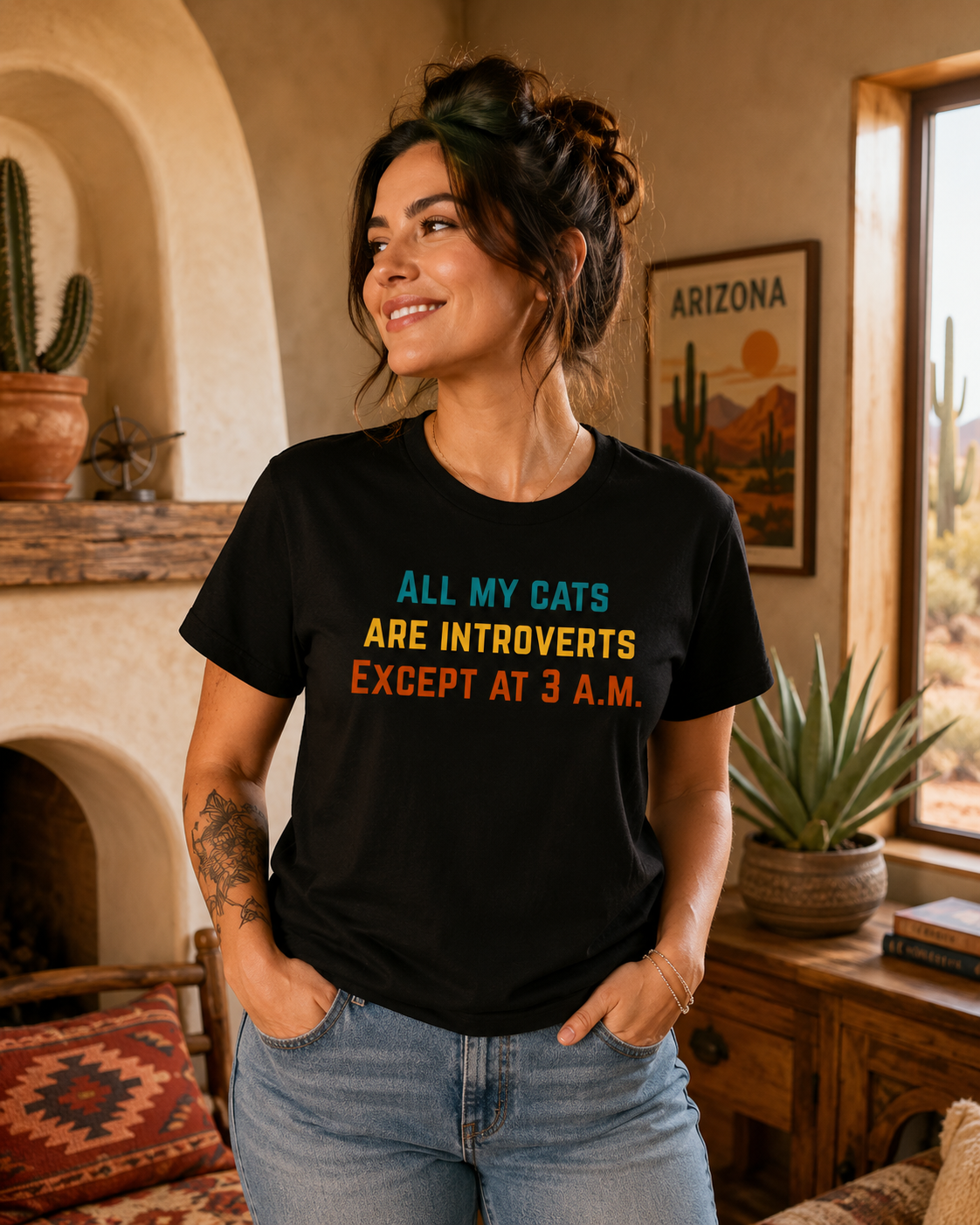 Female model wearing a black cat humor T-shirt in a cozy Arizona-inspired room with cactus decor, warm tones, and desert style.