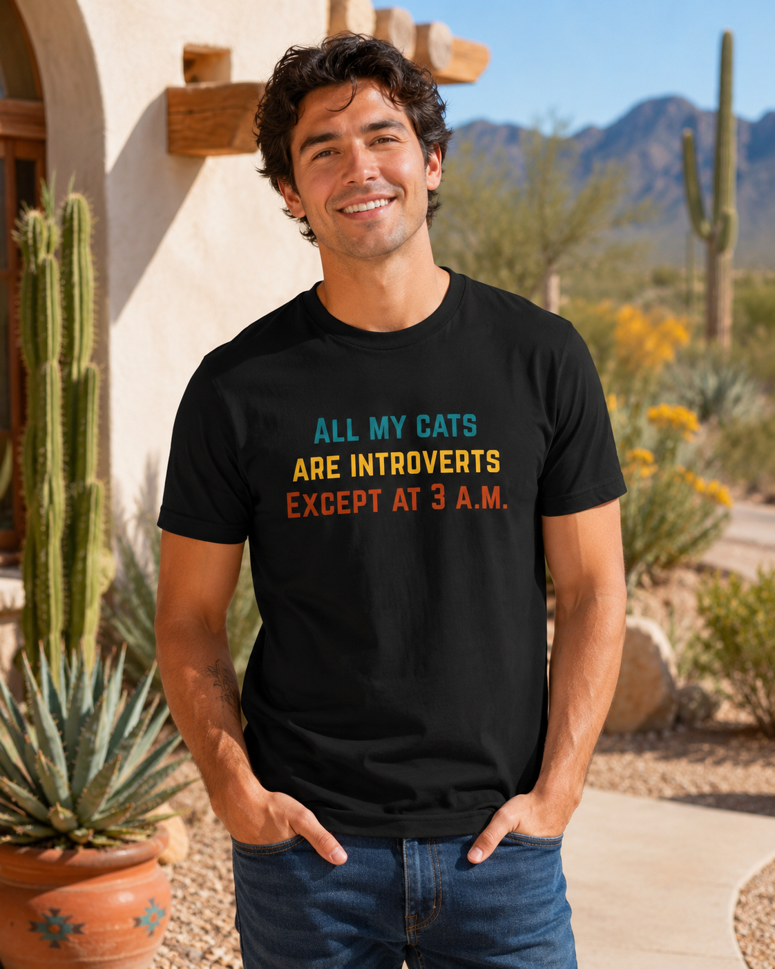 Male model wearing a black funny cat T-shirt in an Arizona desert scene with saguaros, mountains, and sunny natural light.