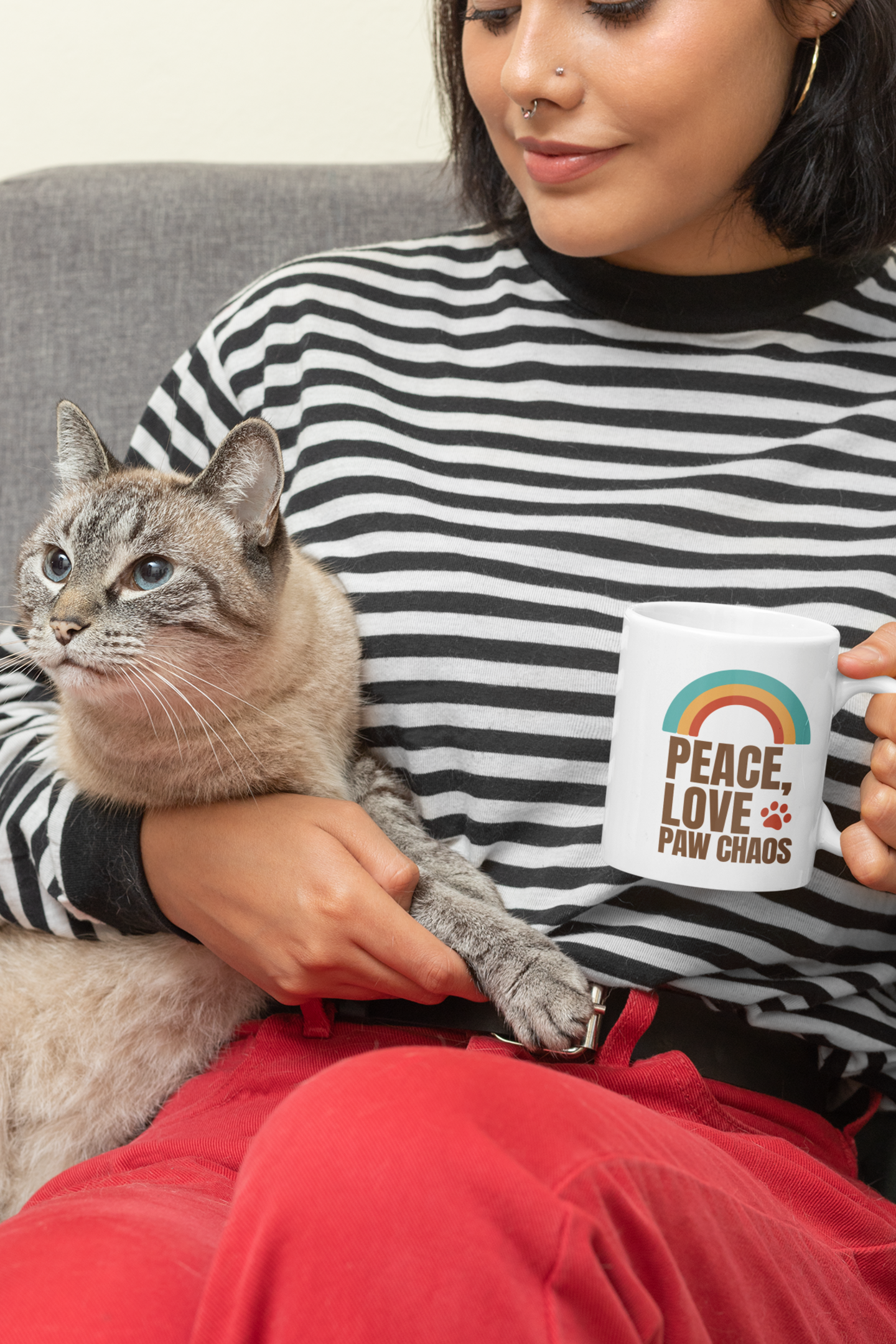 Woman holding a cat and a mug with 'Peace, Love, Paw Chaos' text