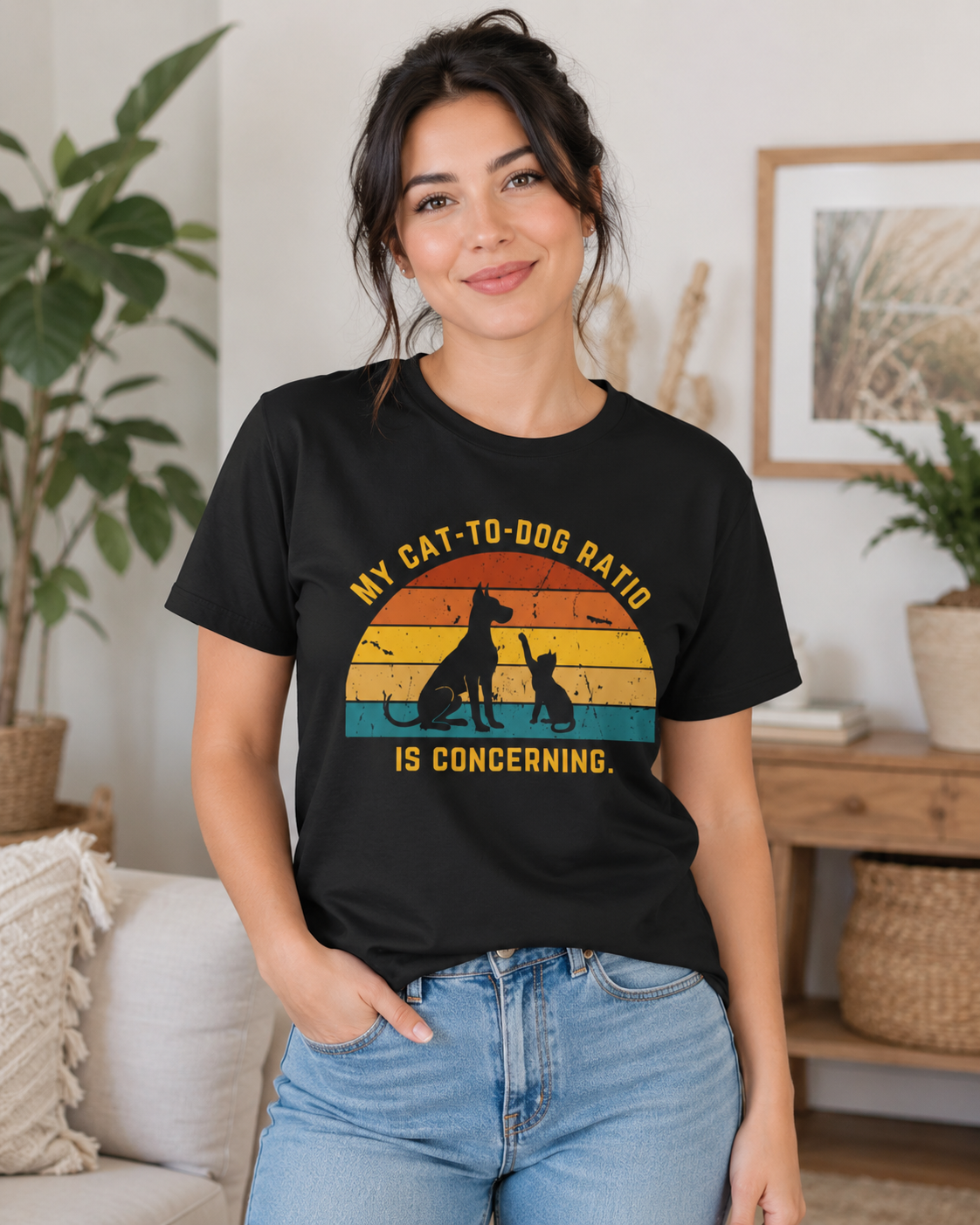 Woman wearing a black My Cat-to-Dog Ratio Is Concerning t-shirt in a cozy indoor apt setting, featuring a retro dog and cat graphic.