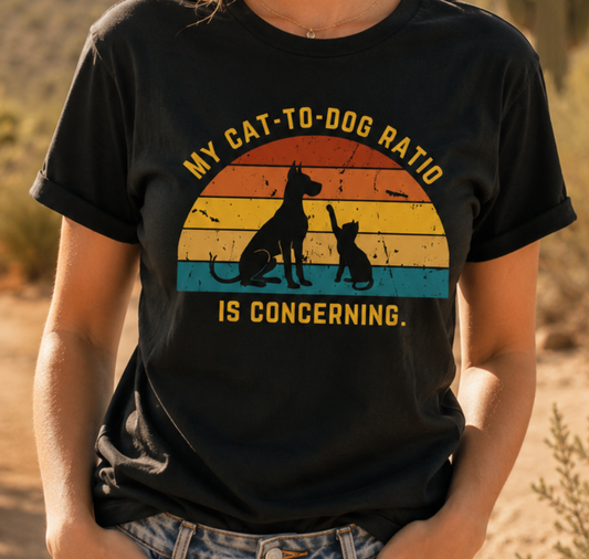 Woman wearing a black My Cat-to-Dog Ratio Is Concerning t-shirt in a cozy indoor setting, featuring a retro dog and cat graphic.