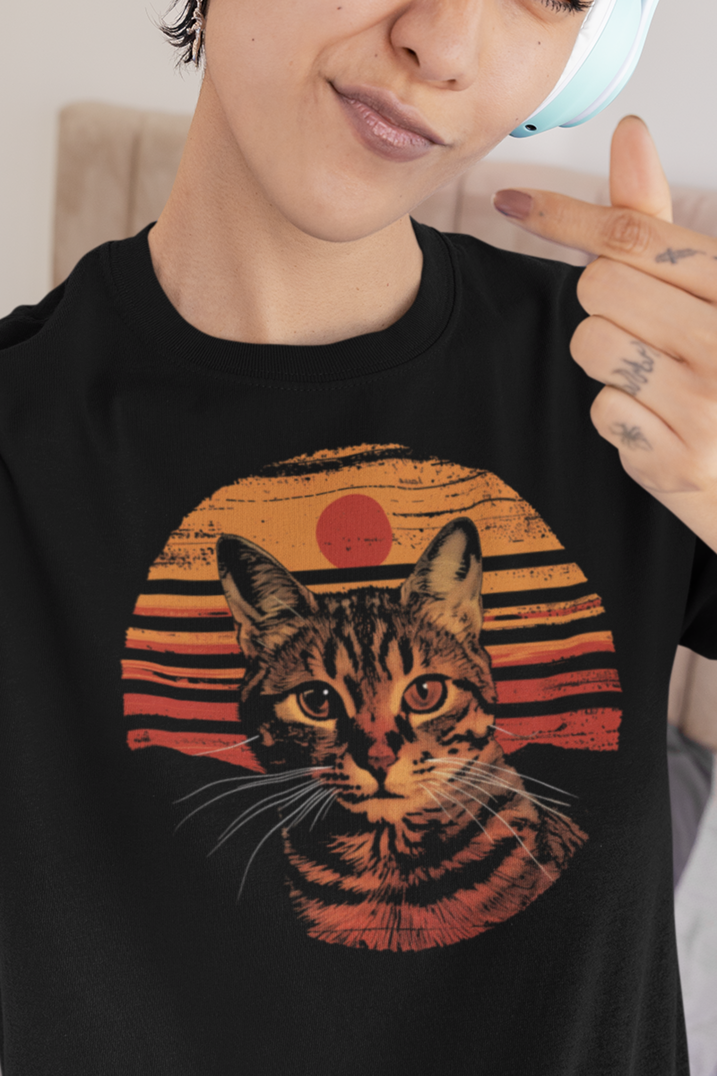 Person wearing a black t-shirt with a tabby cat graphic and retro sunset design.