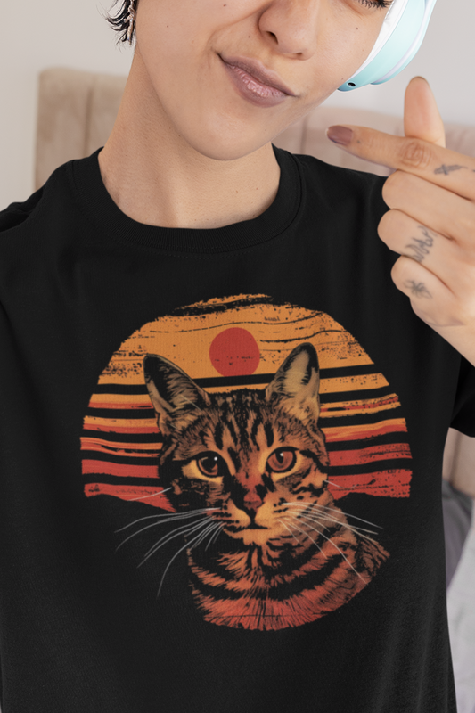 Person wearing a black t-shirt with a tabby cat graphic and retro sunset design.